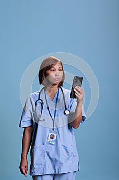 Physician nurse holding mobile phone talking with remote doctor during online videocall