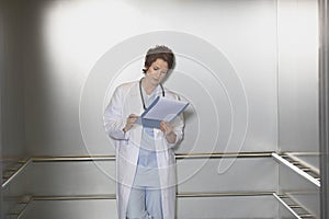 Physician Reviewing Notes In Elevator