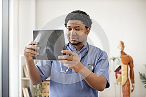 Physician in scrubs scanning X-ray image in clinic's office
