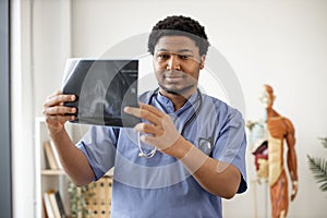 Physician in scrubs scanning X-ray image in clinic's office