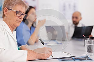 Physician senior woman in white coat analyzing medical examination