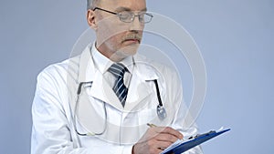 Physician with serious face writing in paper documents, keeping medical records