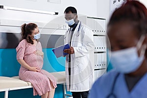 Physician showing checkup papers to pregnant woman