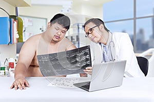 Physician showing x-ray to overweight person