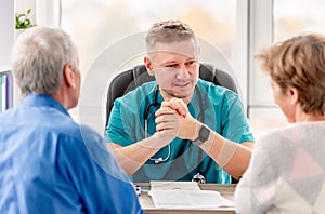 Physician talking to mature couple in cabinet