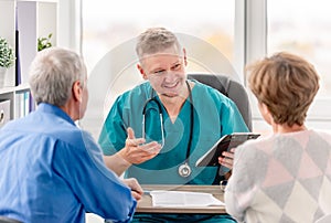Physician talking to mature couple in cabinet