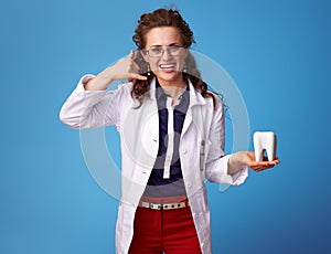 Physician woman showing call me gesture and tooth on blue