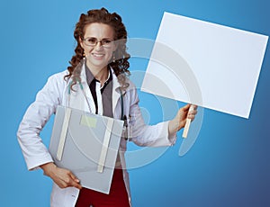 Physician woman with weight scale showing blank placard on blue