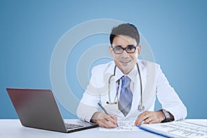 Physician working on desk over blue background