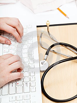 Physician works on white PC keyboard