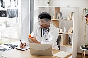 Physician writing prescription at office desk in hospital