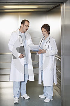 Physicians Discussing Chart In Hospital Elevator