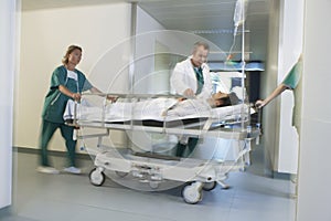 Physicians Moving Patient On Gurney Through Hospital Corridor