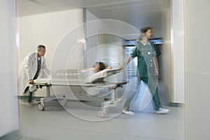 Physicians Moving Patient On Gurney Through Hospital Corridor photo