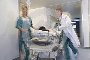 Physicians Moving Patient On Gurney Through Hospital Corridor photo