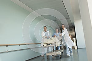 Physicians Rushing Patient On Gurney Down Hospital Corridor photo