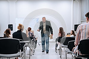 During a physics test in college, a professor in a jacket walks around the audience and communicates with students who