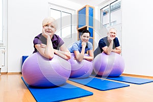 Physio showing senior couple how to use gym ball for exercises