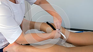 Physiotherapist applying kinesiology tape to woman's leg to fix the calf muscle.