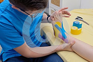 Physiotherapist applying kinesiology tapes on leg photo