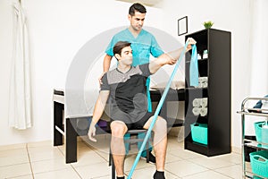 Physiotherapist Assisting Athlete In Performing Stretching Exercise With Resistance Band