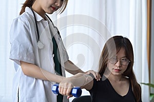 Physiotherapist assisting patient exercising with dumbbell in rehabilitation clinic.