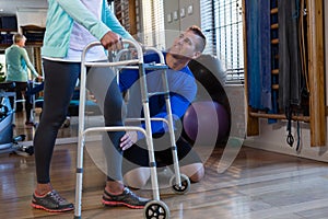 Physiotherapist assisting patient to walk with walking frame