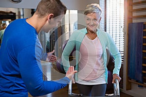 Physiotherapist assisting patient to walk with walking frame