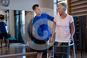 Physiotherapist assisting senior woman patient to walk with walking frame