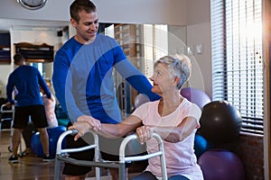 Physiotherapist assisting senior woman patient to walk with walking frame