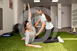 Physiotherapist assisting young caucasian woman with exercise wi