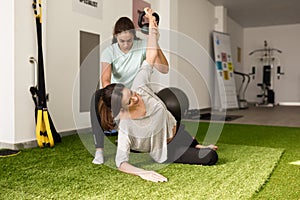 Physiotherapist assisting young caucasian woman with exercise wi