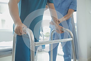 Physiotherapist assists her contented senior patient on folding walker. Recuperation for elderly, seniors care, nursing home