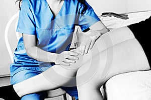 Physiotherapist, chiropractor doing a patellar mobilization, Knee pain in silhouette, color and black and white photo