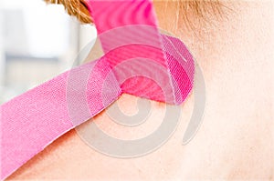 Physiotherapist, chiropractor putting on pink kinesio tape on woman patient. Cervical