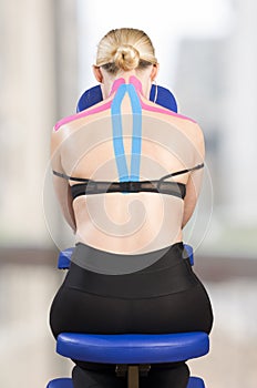 Physiotherapist, chiropractor putting on pink kinesio tape on woman patient. Pink: cervical, trapezius, supraspinatus, blue: high