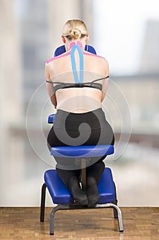 Physiotherapist, chiropractor putting on pink kinesio tape on woman patient. Pink: cervical, trapezius, supraspinatus, blue: high