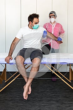 Physiotherapist does pressure and massage exercises on patient with mask and glove for prevention of pandemic coronavirus, covid-