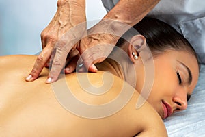 Physiotherapist doing curative back massage along spine on female patient