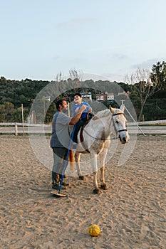 Physiotherapist doing an exercise with a child with a disability in an equine therapy session.