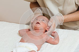 Physiotherapist doing a positional plagiocephaly correction on a newborn baby in a therapy center.