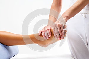 Physiotherapist doing reflexology massage on female foot.