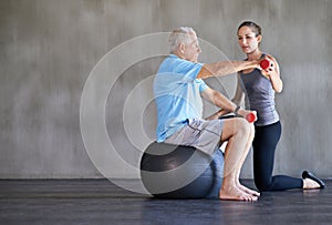 Physiotherapist, dumbbells and senior man on ball for fitness, rehabilitation or exercise at gym on mockup space