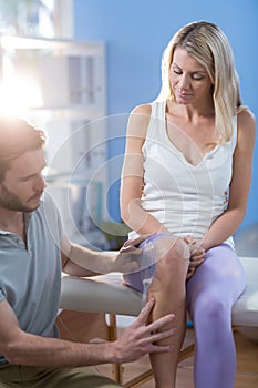 Physiotherapist examining female patients knee with goniometer