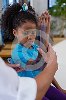 Physiotherapist examining girl patients wrist with goniometer