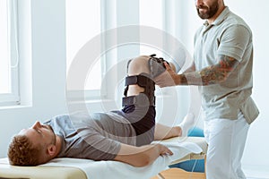 Physiotherapist exercises in a bright medical office with his injured patient