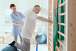 Physiotherapist exercises in a bright medical office with his injured patient