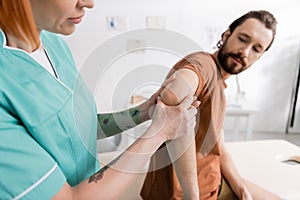 physiotherapist flexing painful elbow of bearded