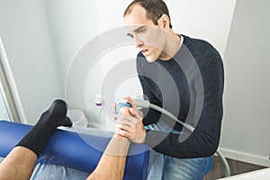 Physiotherapist giving foot therapy to a patient in the clinic. Advanced Physiotherapy Concept