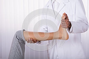 Physiotherapist Giving Leg Exercise To Patient